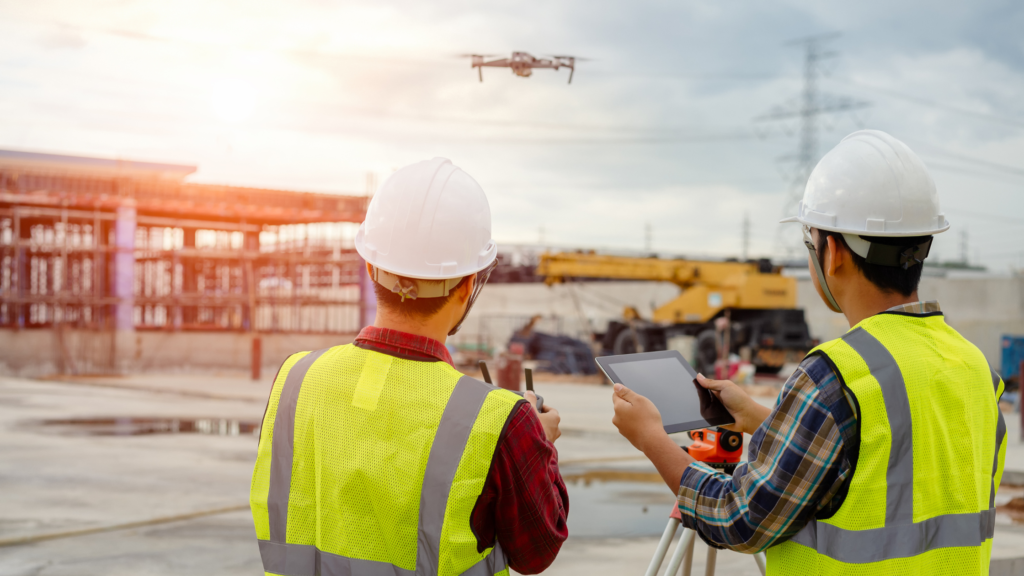 Two construction workers flying a drone in a construction zone.